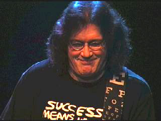 Geoff plays this gig wearing his spectacles, and apparently sporting an optician's sight-testing chart on his guitar-strap